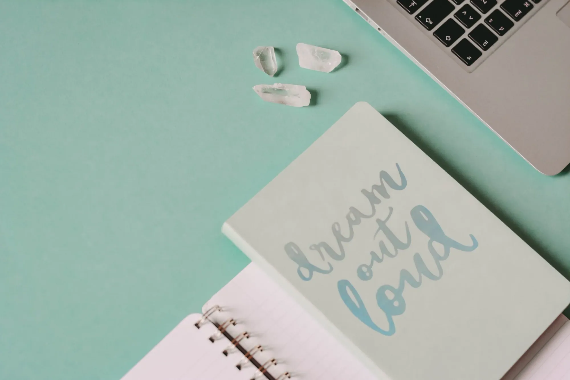 Mint desk flat lay with a laptop and a dream out loud notebook