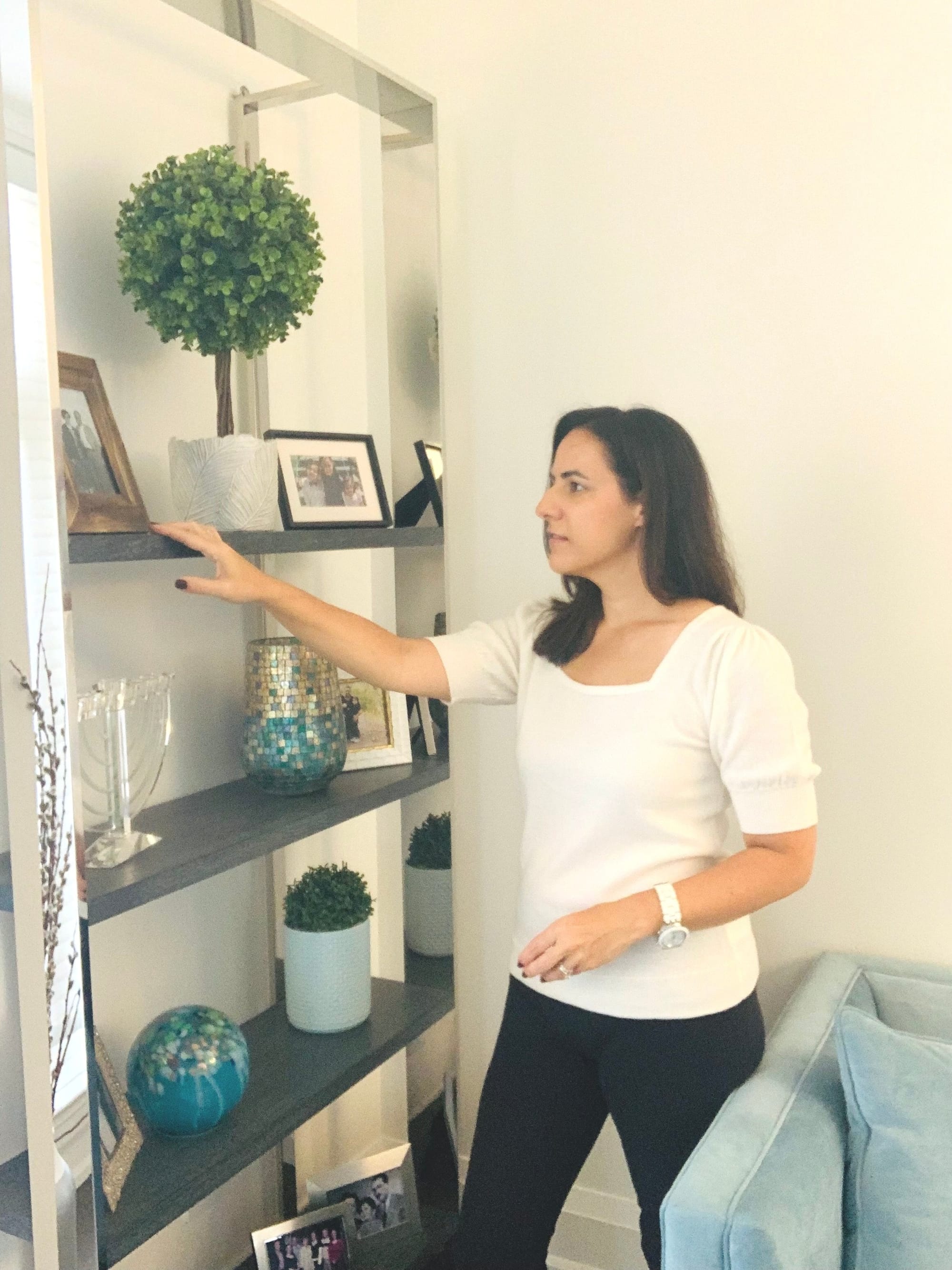 Home organizer arranging decor on a grey shelving unit