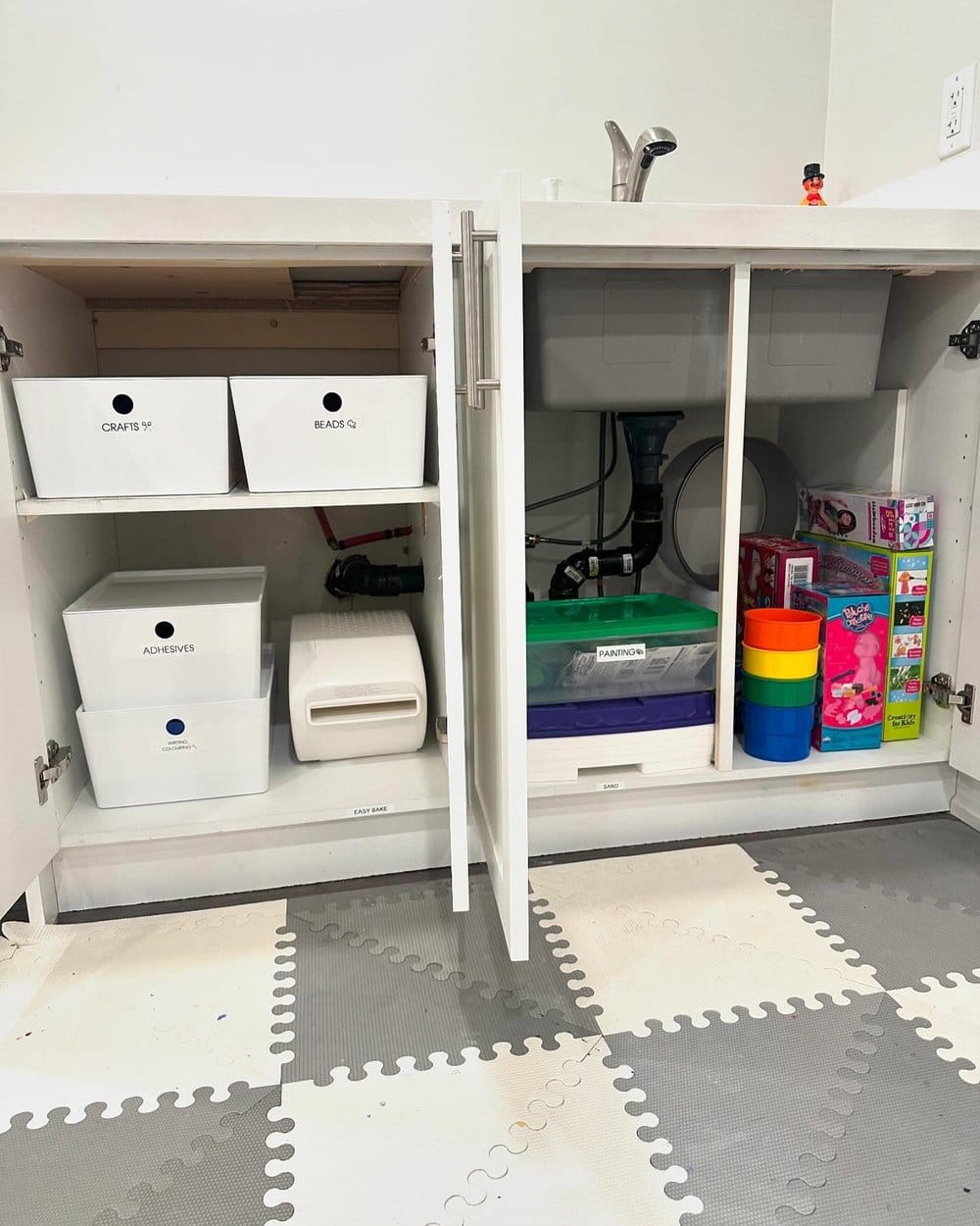 Under-sink cabinet with labelled bins of children's craft supplies