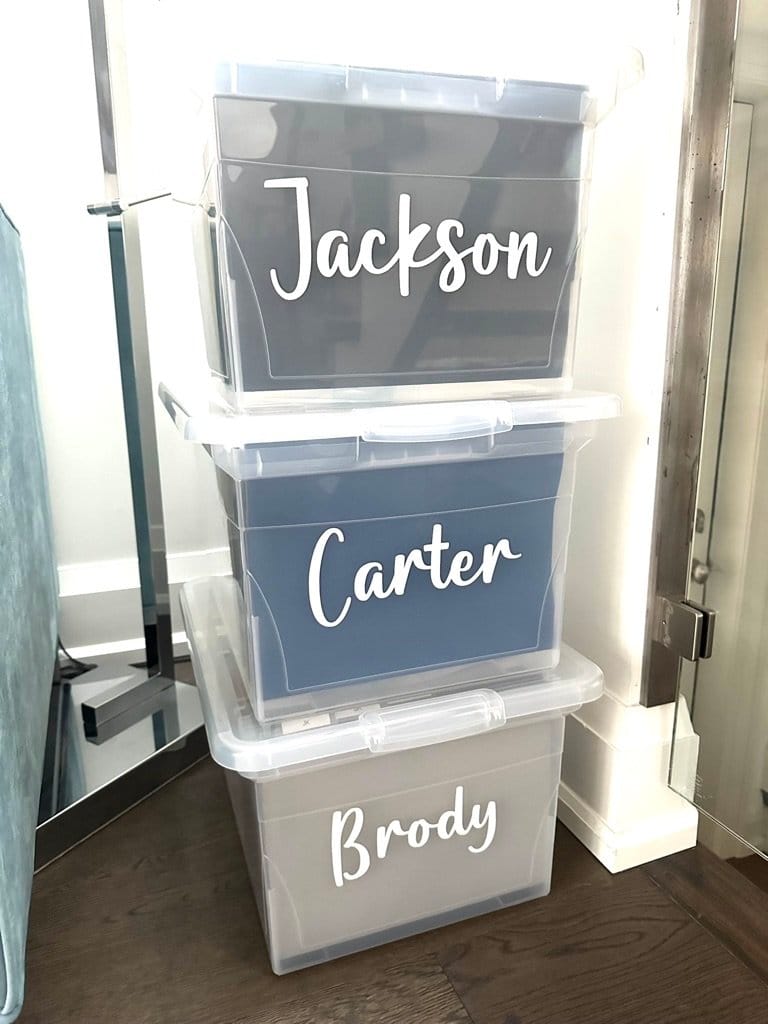 Three clear memory bins labelled Jackson, Carter and Brody in a closet