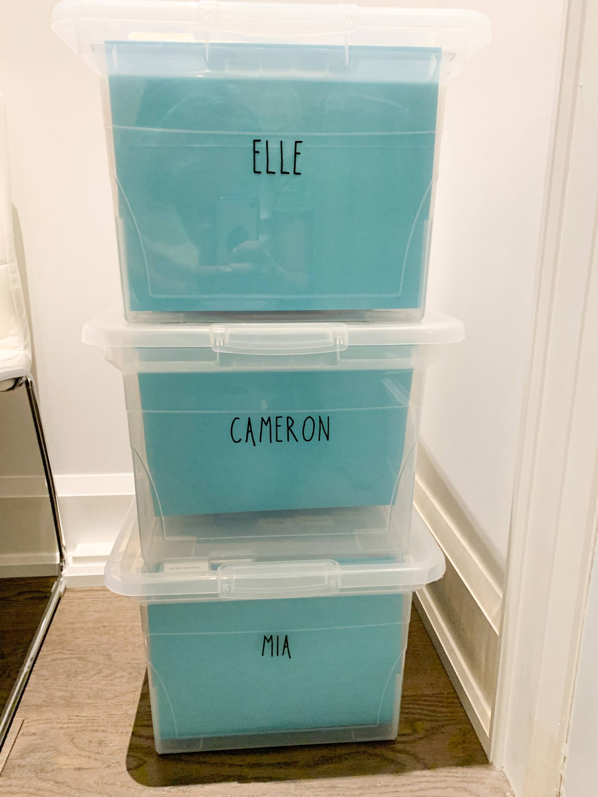 Stacked clear memory bins labelled Elle, Cameron and Mia