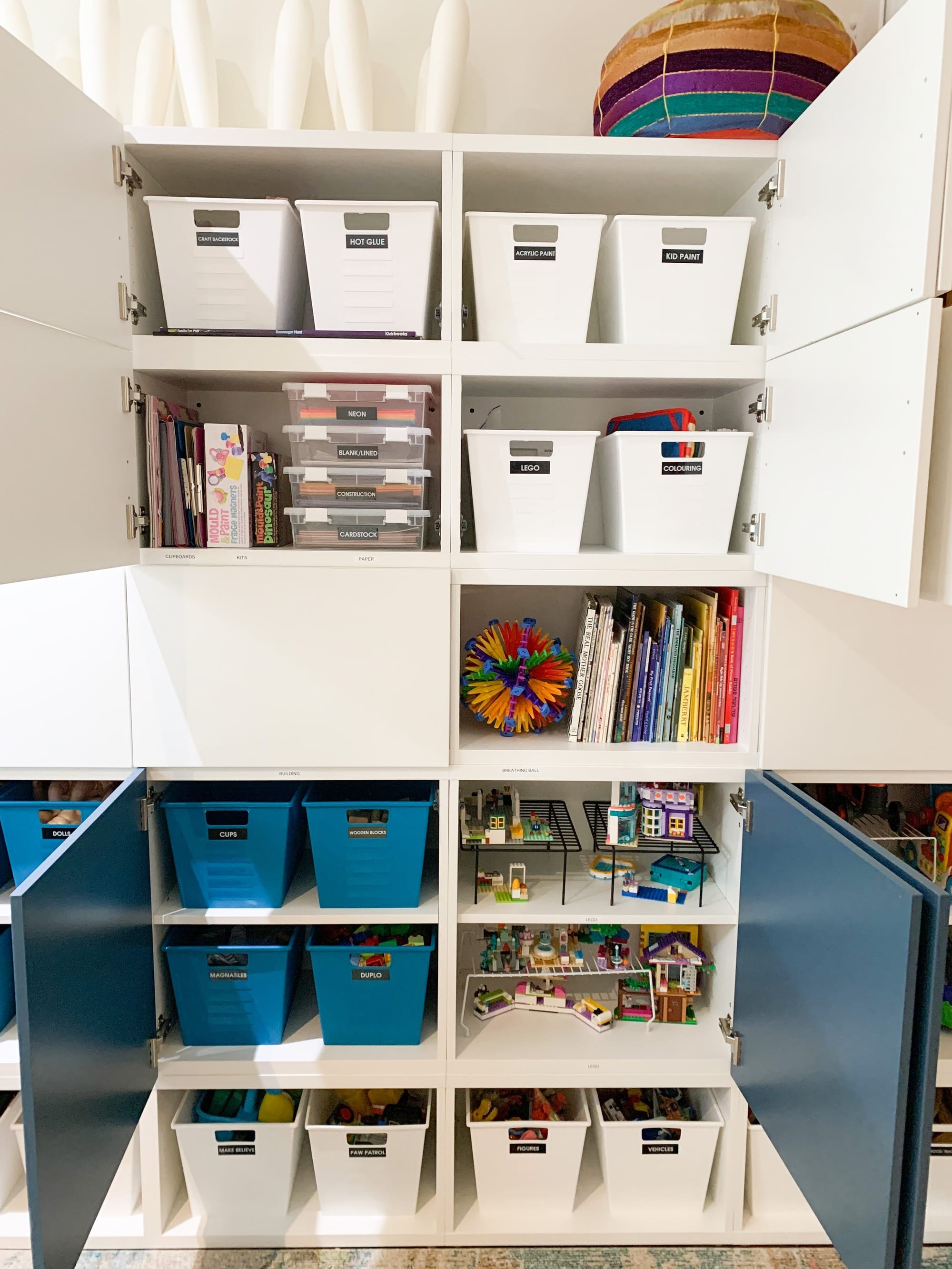 Organized craft and toy cabinet with labelled bins, books and Lego