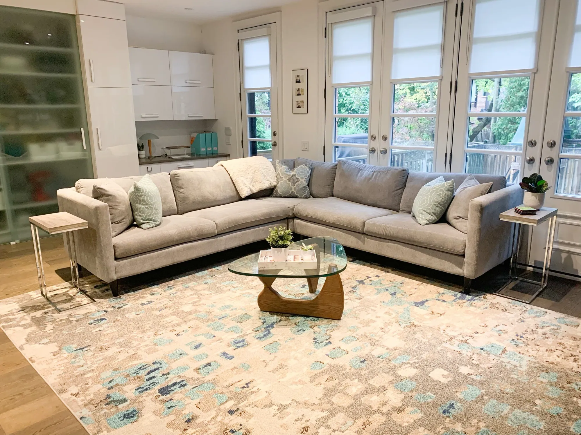 Tidy bright living room with a grey sectional and glass coffee table