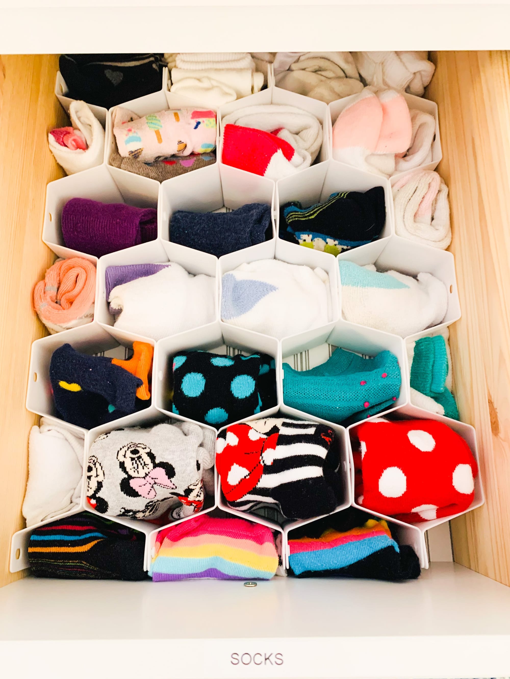 Drawer organized with honeycomb dividers full of rolled socks